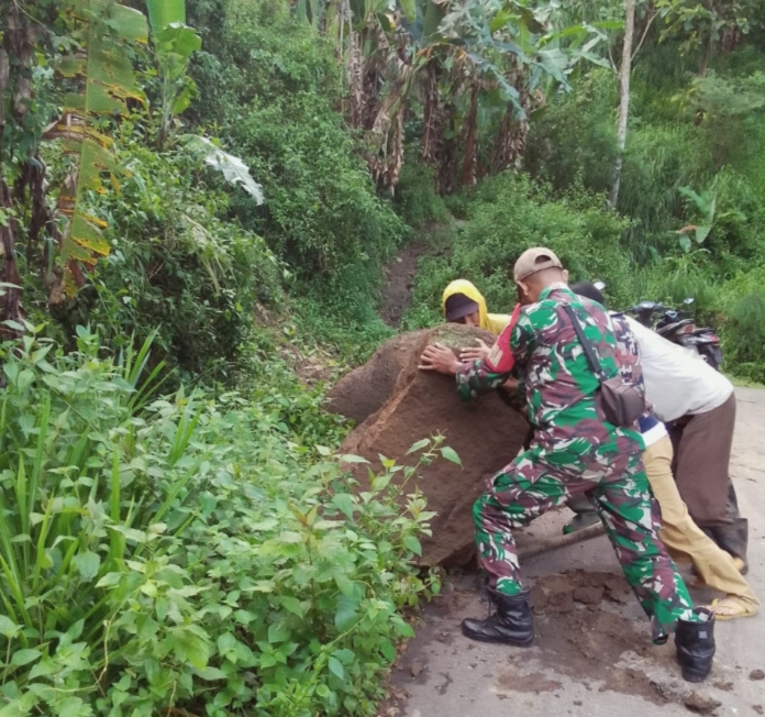 Anggota TNI Koramil Arjasa Bersihkan Sisa Batu Longsor di desa Curah Tatal